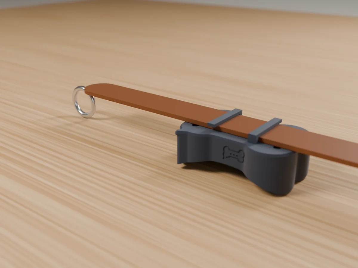 Render of the Bark Tag: a small graphite bone-shaped tag clipped onto a tan leather collar on an oak table.